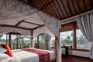 a bedroom with a canopy bed in a room with windows at Santi Mandala Villa & Spa in Sukawati +119 photos