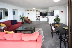 a living room with a red couch and a table at Broadwater Shores Waterfront Apartments in Gold Coast