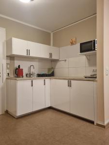 eine Küche mit weißen Schränken und einer Mikrowelle in der Unterkunft Aparthotel Magnolia in Oberursel
