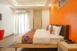 1 dormitorio con 1 cama grande y pared de color naranja en FabHotel Spark Inn I, en Gurgaon