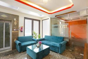 a living room with two blue couches and a table at FabHotel The Indian in Gurgaon +31 photos