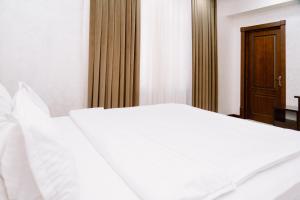 um quarto com uma cama branca e uma porta de madeira em PGA Hotel Free Shuttle to Airport em Tashkent