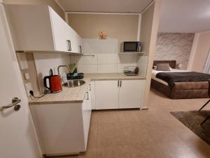 eine Küche mit weißen Schränken und ein Bett in einem Zimmer in der Unterkunft Aparthotel Magnolia in Oberursel