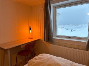 a bedroom with a window and a chair next to a bed at Grand seaview house Ilulissat in Ilulissat