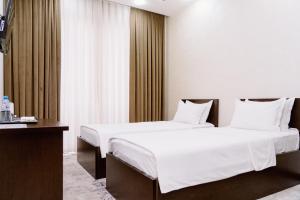 duas camas num quarto de hotel com lençóis brancos em PGA Hotel Free Shuttle to Airport em Tashkent