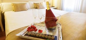 een dienblad met twee wijnglazen en een kaars op een bed bij Hotel Condes de Haro in Logroño