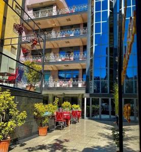 un edificio con mesas rojas y sillas delante de él en Hotel Elysee, en Tirana