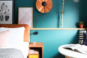a bedroom with a blue wall with a bed and a clock at Hotel Indigo Antwerp City Centre, an IHG Hotel in Antwerp
