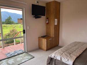 a bedroom with a bed and a television and a balcony at Carrickfergus Cottage Unit 1 in Harihari