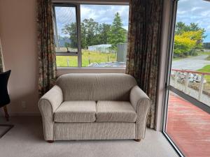 a couch sitting in front of a large window at Carrickfergus Cottage Unit 1 in Harihari +1 photo