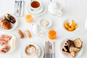 un tavolo bianco con piatti di cibo e tazze di caffè di Hotel Cristallo a Riccione