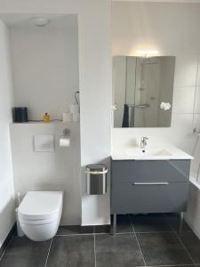 biała łazienka z toaletą i umywalką w obiekcie Maison moderne à 25 minutes du centre Paris et JO 2024 w mieście Eaubonne