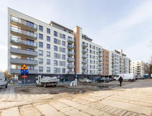 a large building in a parking lot with cars at Letnicka Cosy Apartment with Garden in Gdańsk