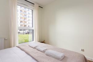 a bedroom with a large window with two towels on a bed at Letnicka Cosy Apartment with Garden in Gdańsk