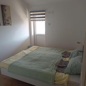 1 dormitorio con 1 cama con edredón verde y ventana en STAN NA DAN en Zaječar