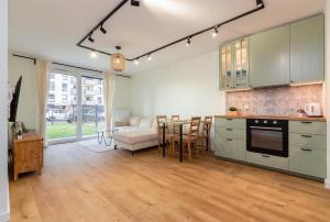 a kitchen and living room with a couch and a table at Letnicka Cosy Apartment with Garden in Gdańsk
