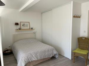 1 dormitorio con 1 cama y 1 silla en Les Côteaux de la Grange, en Mercuer