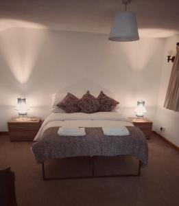 a bedroom with a large bed with two lamps at the lodge@ beechwood house in Mossley