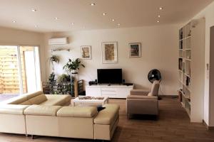 uma sala de estar com um sofá e uma televisão em A l'ombre du Saule. Villa 10 personnes + piscine em Saint-Romain-en-Viennois
