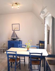 une salle à manger avec une table blanche et des chaises bleues dans l'établissement La goélette - Les Gîtes de la Côte d'Amour, au Croisic