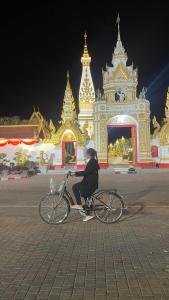 een persoon die fietst voor een gebouw bij Pharungruang House Thatphanom Nakonphanom พารุ่งเรืองเฮ้าส์ in That Phanom