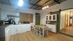 a kitchen with white cabinets and a table with chairs at Pharungruang House Thatphanom Nakonphanom พารุ่งเรืองเฮ้าส์ in That Phanom