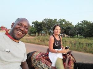 a man and a woman sitting on a horse on a road at CHEZ ALFA in Jugu
