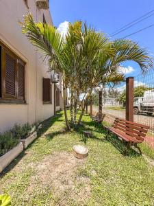 un banco de parque y palmeras en un patio en Apartamento Amplo em Capão da Canoa, en Capão da Canoa