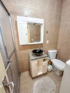y baño con lavabo, aseo y espejo. en Apartamento Amplo em Capão da Canoa, en Capão da Canoa