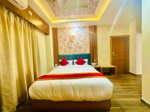 Hotel Ultra International في بهيراهاوا: غرفة نوم بسرير كبير ومخدات حمراء
