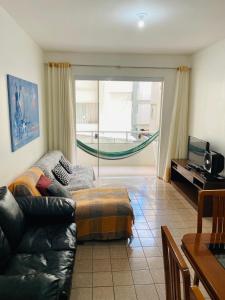 ein Wohnzimmer mit einem Sofa und einem TV in der Unterkunft Ap férias - 2 qt - Wi-Fi - Guarapari - Praia do Morro in Guarapari