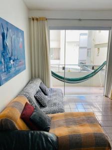 ein Wohnzimmer mit einem Sofa und einer Glasschiebetür in der Unterkunft Ap férias - 2 qt - Wi-Fi - Guarapari - Praia do Morro in Guarapari