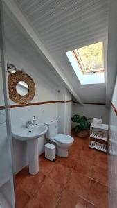 ein Badezimmer mit einem WC, einem Waschbecken und einem Dachfenster in der Unterkunft LA CRUZ DE LA ATALAYA in Benamahoma