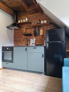 Il comprend une cuisine équipée d'un réfrigérateur noir et d'une cuisinière. dans l'établissement Górskie apartmenty Kowary, à Kowary