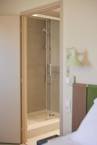 a glass shower stall in a room with a bed at Hotel des Victoires - Restaurant in Cannes