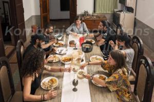 un grupo de personas sentadas alrededor de una mesa comiendo comida en Dutch Square Hostel en Alleppey