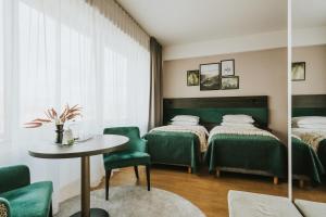 a room with two beds and a table and chairs at Green Hotel in Inowrocław