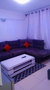 a living room with a purple couch with red pillows at Serene Safaris Airbnb in Thika in Thika