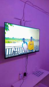 a tv on a purple wall with two men on it at Serene Safaris Airbnb in Thika in Thika