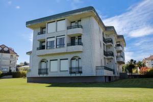 un gran edificio blanco con balcones en el césped en Apartamentos Salceda, en Noja