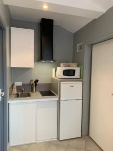 eine Küche mit weißen Schränken und einer Mikrowelle in der Unterkunft Les Ouches in Fleurey-sur-Ouche
