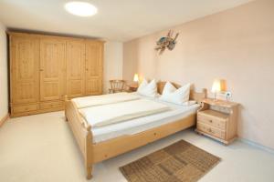 ein Schlafzimmer mit einem großen Bett und einem Holzschrank in der Unterkunft Gästehaus Bergfrieden in Bolsterlang