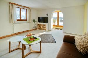 ein Wohnzimmer mit einem Sofa und einem Tisch in der Unterkunft Gästehaus Bergfrieden in Bolsterlang