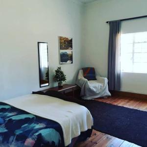 a bedroom with a bed and a chair and a window at Frosty Peaks Farmstay in Barkly East
