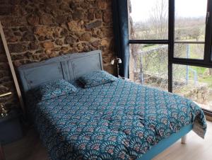 een bed in een kamer met een stenen muur bij La Verdine in Vérin