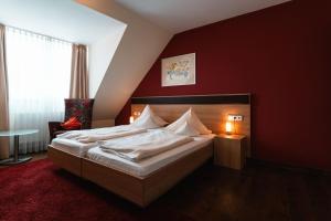 sypialnia z dużym łóżkiem z czerwoną ścianą w obiekcie Landhotel und Weingasthof Schwarzer Adler w mieście Wiesenbronn