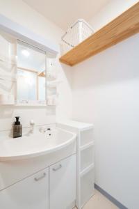 a white bathroom with a sink and a mirror at ILIMA Higashi Nakano in Tokyo