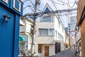 - une vue sur la rue d'un bâtiment blanc avec beaucoup de fils dans l'établissement ILIMA Higashi Nakano 新宿から電車で5分 東中野駅まで徒歩2分 最大4人 洗濯機 ダイニングキッチン 電子レンジ, à Tokyo