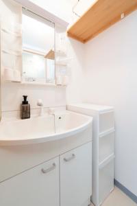 une salle de bains blanche avec un lavabo et un miroir dans l'établissement ILIMA Higashi Nakano 新宿から電車で5分 東中野駅まで徒歩2分 最大4人 洗濯機 ダイニングキッチン 電子レンジ, à Tokyo 43 autres photos