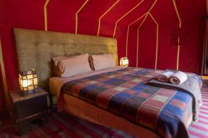 Erg Chegaga Desert Standard Camp في Mhamid: غرفة نوم بسرير في خيمة حمراء